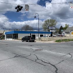 Street view of building with blue roof, sky above and black truck out front