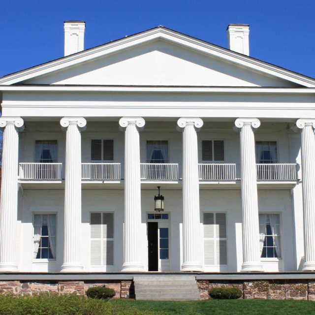 Front view of Pomerleau Real Estate building, white building with six columns